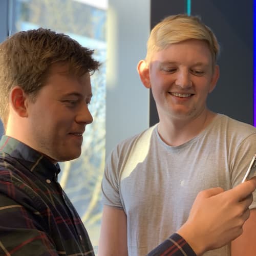 Rasmus og Alexander ser på en telefon og smiler
